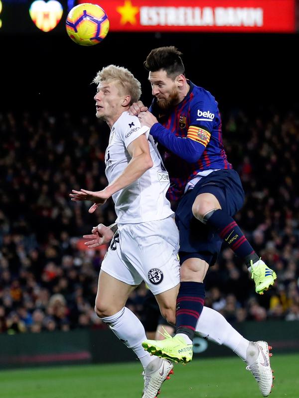Pemain Barcelona, Lionel Messi (kanan) berebut bola udara dengan pemain Valencia Carlos Soler saat bertanding dalam lanjutan Liga Spanyol di Camp Nou, Spanyol, Minggu (3/2). Dua gol Messi membuat pertandingan berakhir 2-2. (AP Photo/Manu Fernandez)