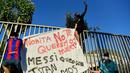 Suporter memanjat pagar dan memasang spanduk saat protes di depan kantor Barcelona, Rabu (26/8/2020). Dalam aksi tersebut fans meminta Lionel Messi bertahan dan menuntut Josep Maria Bartomeu mundur dari jabatannya. (AFP/Pau Barrena)