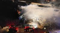 Asap mengepul dari kereta saat petugas pemadam kebakaran dan penyelamat beroperasi setelah tabrakan di dekat kota Larissa, Yunani, Rabu dini hari (1/3/2023). Tim penyelamat tengah bekerja untuk menyelamatkan penumpang dan memadamkan api. (AP Photo/Vaggelis Kousioras)