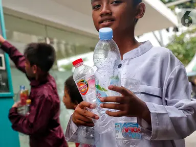 Seorang anak membawa botol plastik bekas untuk dimasukkan ke Reverse Vending Machine (RVM) di halaman Masjid Istiqlal, Jakarta, Senin (5/6/2023). (Liputan6.com/Angga Yuniar)