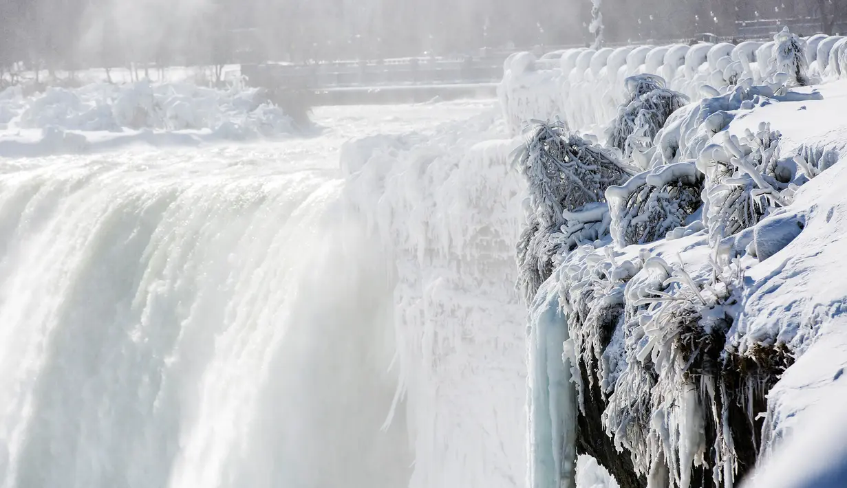 Es dan air mengalir di tepi Horseshoe Falls dari Air Terjun Niagara di Ontario, Kanada, Kamis (31/1). Suasananya yang putih terlihat seperti hamparan kapas saat Air Terjun Niagara diabadikan dari udara. (Tara Walton/The Canadian Press via AP)