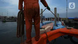 Petugas dari Dinas Lingkungan Hidup DKI Jakarta mengumpulkan sampah di Pelabuhan Kali Adem, Muara Angke, Jakarta, Rabu (6/1/2021). Dalam sehari, sampah pesisir Teluk Jakarta Utara bisa terangkut sekitar 7 kubik sampah plastik yang terbawa dari sungai maupun arus laut. (merdeka.com/Imam Buhori)