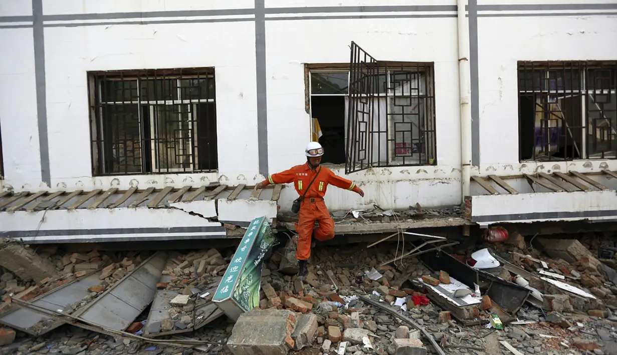 Salah satu anggota tim penyelamat keluar dari gedung yang rusak akibat gempa di Longtoushan, provinsi Yunan, Tiongkok, (6/8/2014). (REUTERS/Stringer)