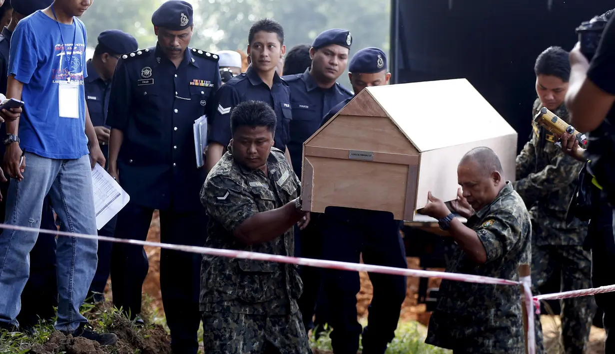 Petugas kepolisian Malaysia membawa peti mati jenazah yang di duga etnis Rohingya ke pemakaman massal di Alor Setar, Malaysia, Senin (22/6/2015).  21 dari 106 jenazah tak dikenal yang ditemukan bulan lalu dimakamkan hari ini. (Reuters/Olivia Harris)