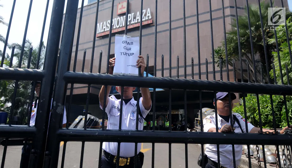 Petugas berjaga di depan Gedung Maspion Plaza, Jakarta Utara, Selasa (4/7). Para pengemudi berunjuk rasa karena akun mereka yang tiba-tiba diputus kemitraannya oleh pihak Grab pada Selasa (27/6). (Liputan6.com/Gempur M Surya)