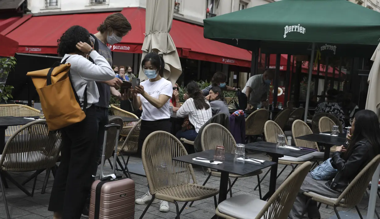 Seorang pramusaji memeriksa kartu kesehatan pengunjung di sebuah restoran di Paris, Senin (9/8/2021). Prancis mewajibkan semua orang menunjukkan kode QR yang membuktikan mereka memiliki Kartu Vaksinasi untuk memasuki restoran dan kafe atau bepergian di negara tersebut. (AP Photo/Adrienne Surprenant