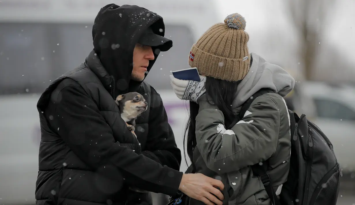 Seorang pengungsi yang melarikan diri dari Ukraina menyeka air mata setelah melihat seorang kerabat di perbatasan Rumania-Ukraina, di Siret, Rumania, Senin, 7 Maret 2022. (AP Photo/Andreea Alexandru)