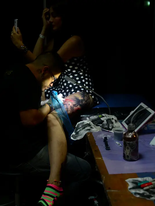 Seniman membuat tato di bagian kaki seorang wanita saat acara Expotattoo Colombia 2016 di Medellin, Kolombia, (16/7). Sejumlah wanita tampak antusias untuk mentato tubuhnya di festival tato terbesar di negara tersebut. (AFP PHOTO/RAUL Arboleda)