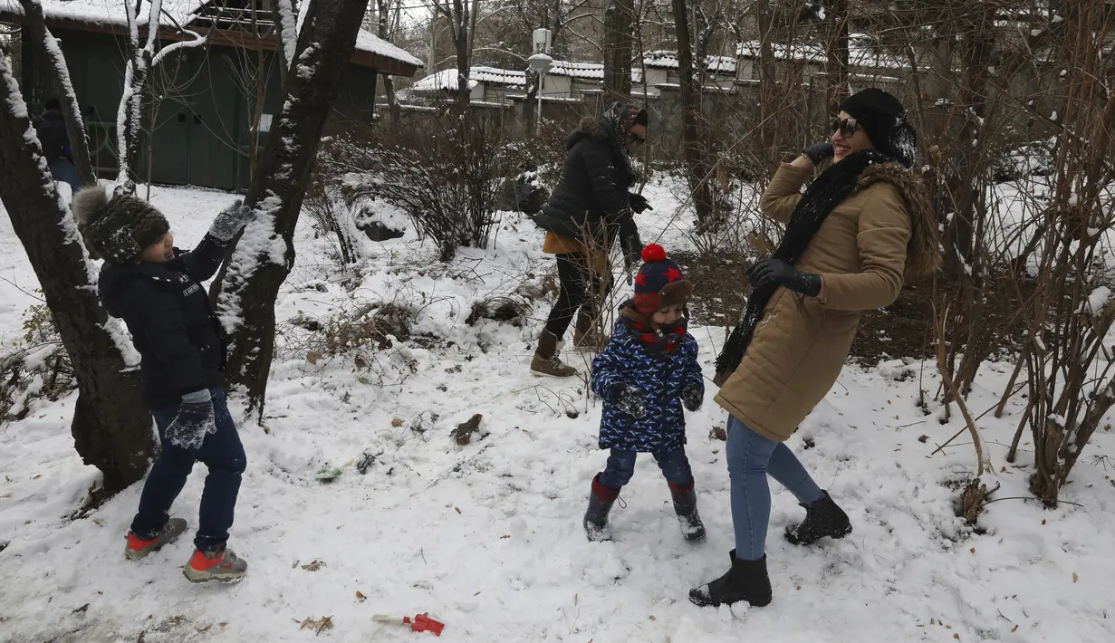 Orang-orang bermain dengan salju saat menghabiskan akhir pekan mereka di sebuah taman di Teheran utara, Iran, Jumat (25/12/2020). Iran berjuang melawan virus corona sangat terhambat oleh sanksi AS yang dijatuhkan pemerintahan Donald Trump. (AP Photo/Vahid Salemi)
