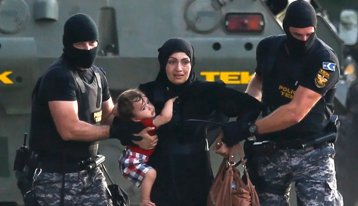 Polisi anti huru-hara mengevakuasi imigran wanita dan anaknya dari bentrokan yang terjadi antara polisi dengan imigran yang berusaha menerobos pintu perbatasan Serbia dan Hungaria di Roszke, Rabu (16/9/2015). (REUTERS/Dado Ruvic)