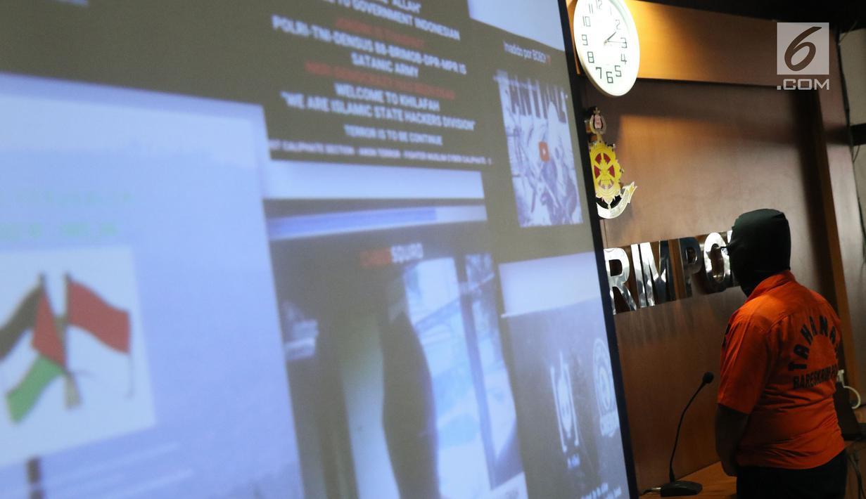 Salah satu tersangka dari kelompok hacker yang meretas situs PN Sulawesi Tenggara serta latar tampilan situs yang berhasil diretas diperlihatkan saat rilis di Bareskrim Mabes Polri, Jakarta, Jumat (9/11). (Liputan6.com/Helmi Fithriansyah)