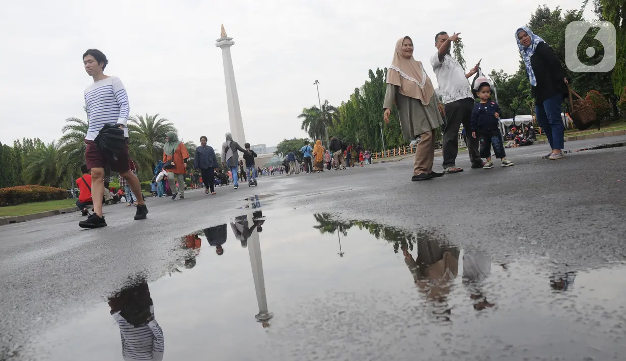 Warga berjalan-jalan di kawasan Monumen Nasional, Jakarta, Rabu (25/12/2019). Libur perayaan Natal 2019 dimanfaatkan warga Jakarta dan sekitarnya berwisata di Monumen Nasional. (Liputan6.com/Helmi Fithriansyah)