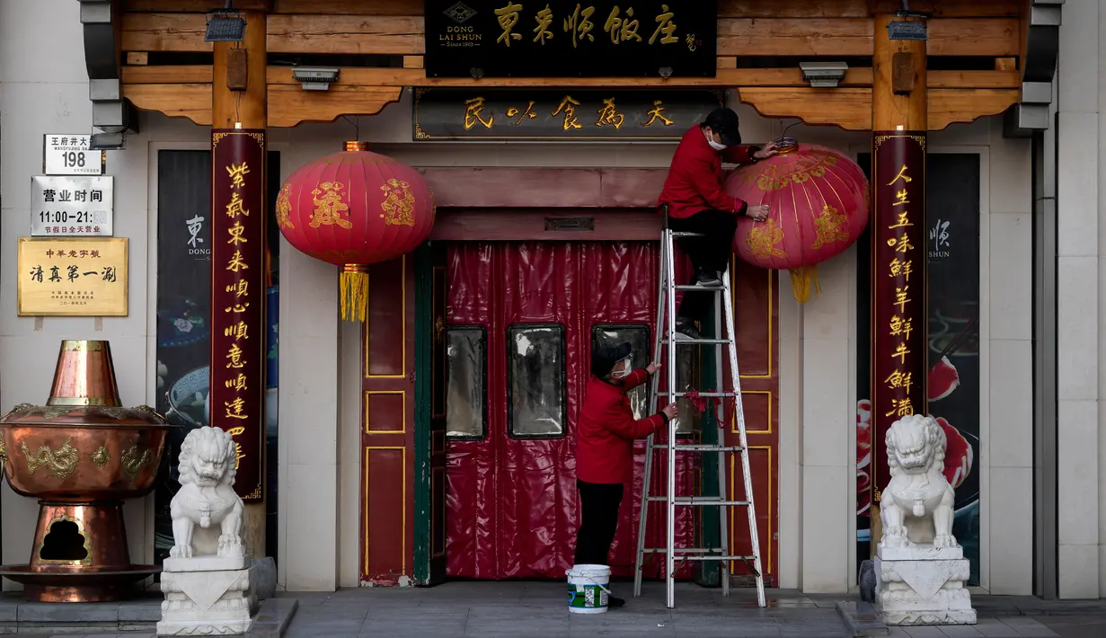 Seorang pekerja yang mengenakan masker membersihkan lentera berdebu di luar restoran di distrik perbelanjaan Wangfujing, Beijing, China, Rabu (14/12/2022). Mulai hari ini, Komisi Kesehatan Nasional China melaporkan penurunan kasus harian COVID-19 sejak pemerintah melonggarkan pengujian PCR setelah kasus harian mencapai rekor tertinggi. (AP Photo/Andy Wong)
