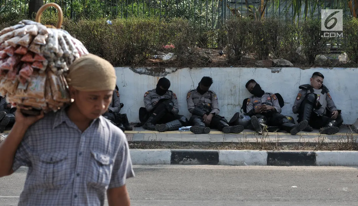 Polisi beristirahat di trotoar akses menuju Gedung DPR RI di Jalan Gatot Subroto, Jakarta, Kamis (26/9/2019). Polisi menutup jalan mulai dari simpang Gerbang Pemuda guna mengantisipasi adanya aksi unjuk rasa susulan. (merdeka.com/Iqbal S Nugoroho)
