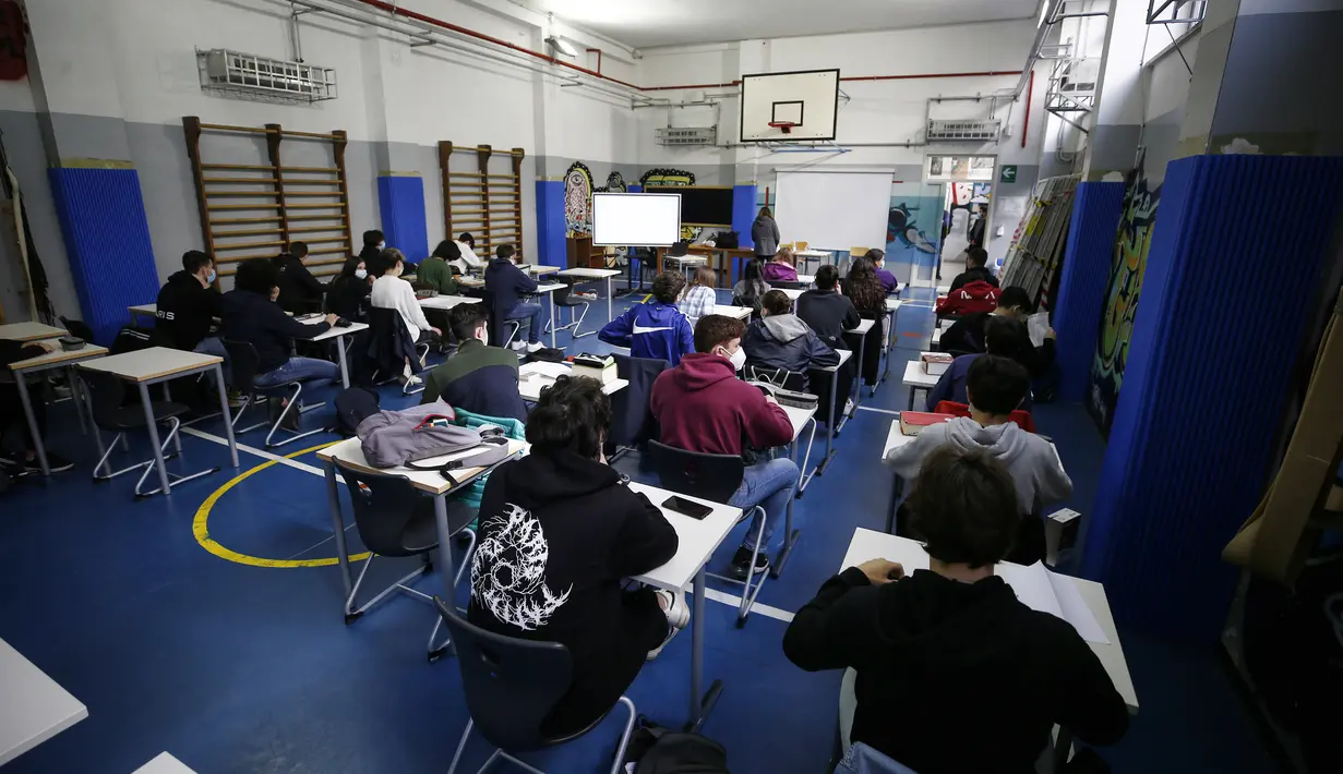 Siswa sekolah menengah menghadiri kegiatan belajar di sebuah gym yang diubah menjadi ruang kelas untuk memungkinkan aturan jarak sosial di Roma, Senin (26/4/2021). Italia kembali dibuka secara bertahap pada hari Senin setelah enam bulan memberlakukan lockdown. (Cecilia Fabiano/LaPresse via AP)