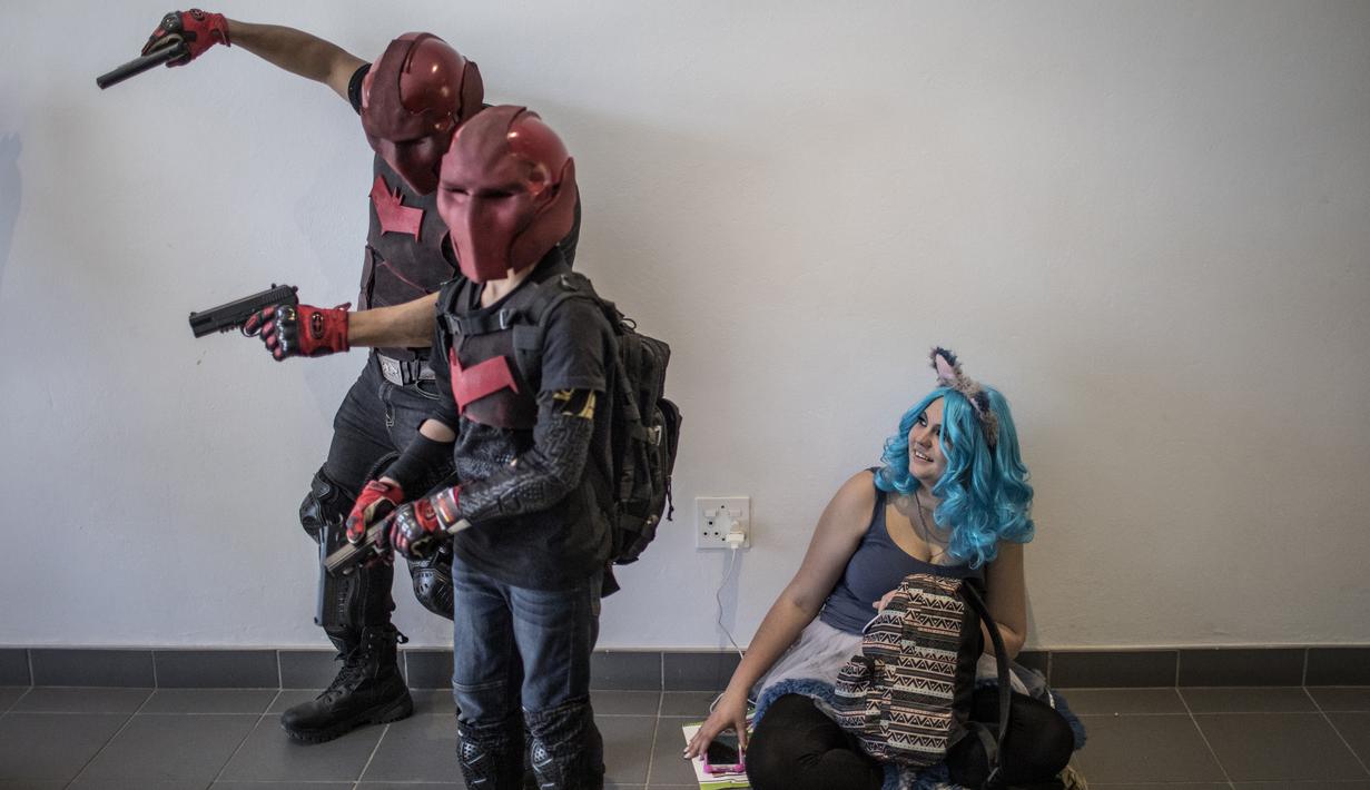 Tiga cosplayer bermain beraksi saat menghadiri International Comic Con di Kyalami Race Course, Johannesburg, Afrika Selatan (14/9). Comic Con digelar pada tahun 1970. (AFP Photo/Marco Longari)