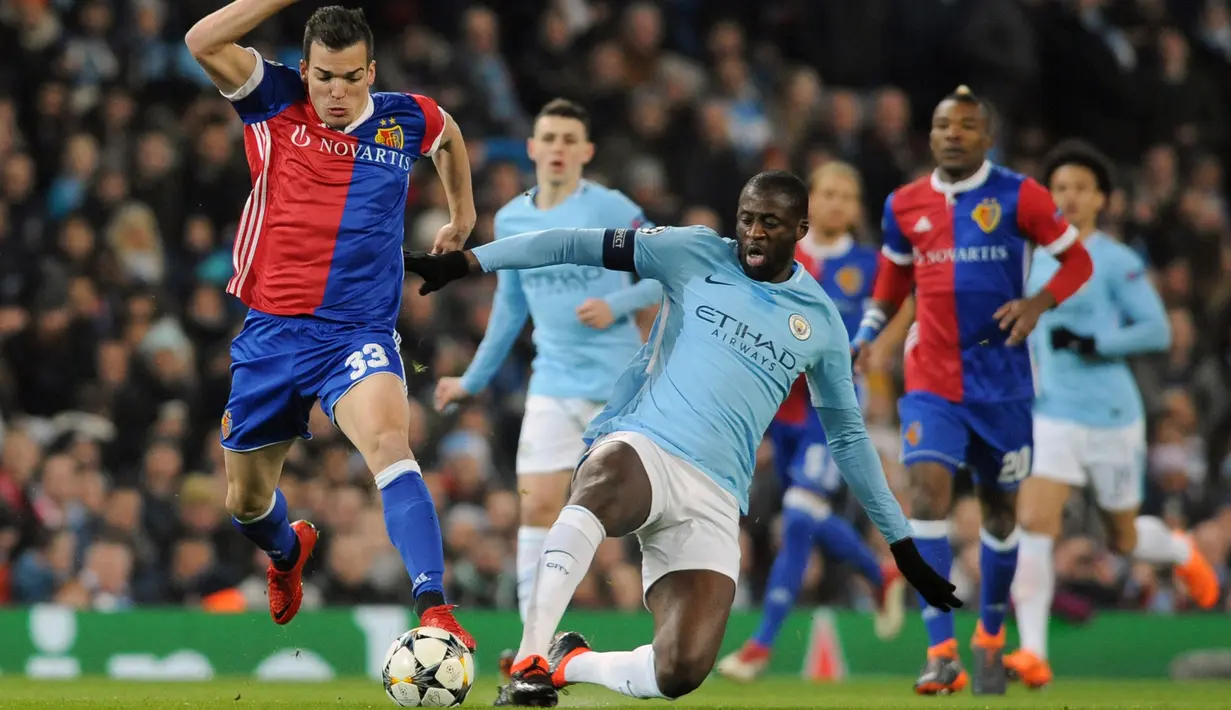Pemain Manchester City Yaya Toure melakukan tackling kepada pemain FC Basel Kevin Bua saat pertandingan Liga Champions leg kedua  di Stadion Etihad, Manchester (7/3). Karena menang agregat,  Manchester City melaju ke perempat final.(AP Photo / Rui Vieira)