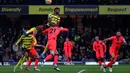 Pemain Watford Emmanuel Dennis melompat di atas pemain Norwich City Brandon Williams untuk menyundul bola dari umpan silang pada pertandingan sepak bola Liga Inggris di Vicarage Road Stadium, Watford, Inggris, Sabtu (22/1/2022). Norwich City menang 3-0. (Adrian DENNIS/AFP)