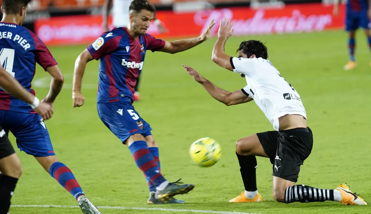 Pemain Levante, Nemanja Radoja menendang bola dari kawalan pemain Valencia, Carlos Soler pada pertandingan La Liga Spanyol di Stadion Mestalla di Valencia, Spanyol, Minggu, (13/9/2020). Valencia menang telak 4-2. (AP Photo/Alberto Saiz)