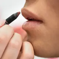 Seorang perempuan sedang mengaplikasikan lip liner di bibirnya (Foto Dok: Freepik/javi_indy).