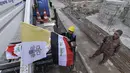 Pekerja mengibarkan bendera Irak dan Takhta Suci Vatikan di tiang-tiang jalan di kota Mosul, Irak, Kamis (4/3/2021). Pemimpin Tertinggi Umat Katolik Paus Fransiskus memulai kunjungan bersejarah ke Irak pada Jumat (5/3), meskipun menghadapi pandemi Covid-19 dan ancaman keamanan. (Zaid AL-OBEIDI/AFP)