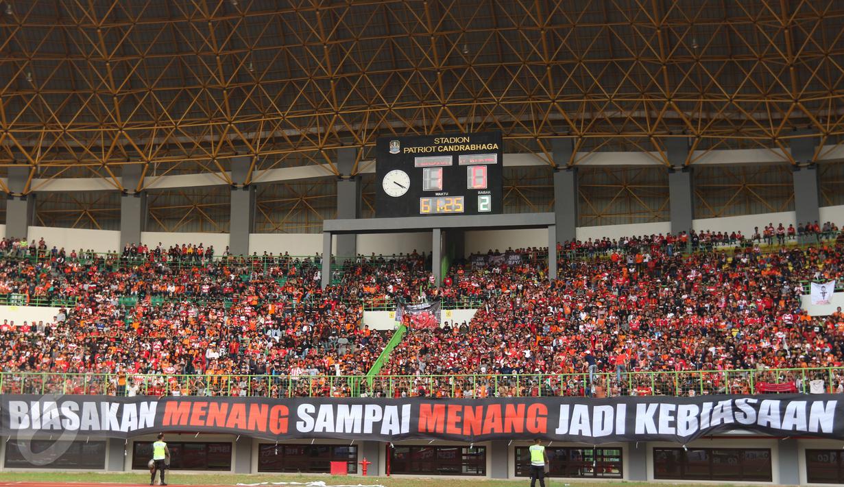 Suporter membentangkan spanduk saat menyaksikan laga Persija melawan Mitra Kukar pada lanjutan Liga 1 Indonesia di Stadion Patriot Candrabhaga, Bekasi, Minggu (14/5). Laga kedua tim berakhir imbang 1-1. (Liputan6.com/Helmi Fithriansyah)