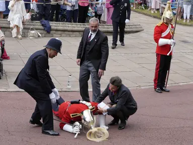 Seorang prajurit yang pingsan mendapat pertolongan segera jelang kebaktian Order of the Garter di Windsor Castle, di Windsor, Inggris, Senin, 19 Juni 2023. Order of the Garter adalah Order of Chivalry tertua dan paling senior di Inggris, yang didirikan oleh Raja Edward III hampir 700 tahun yang lalu.(AP Photo/Kirsty Wigglesworth, Pool)