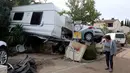Seorang wanita berjalan di dekat mobil dan karavan yang rusak akibat banjir bandang yang disebabkan hujan deras di Biot, Prancis, Minggu (4/10/2015). Akibat peristiwa itu, sebanyak 16 warga dilaporkan tewas. (REUTERS/Eric Gaillard)   