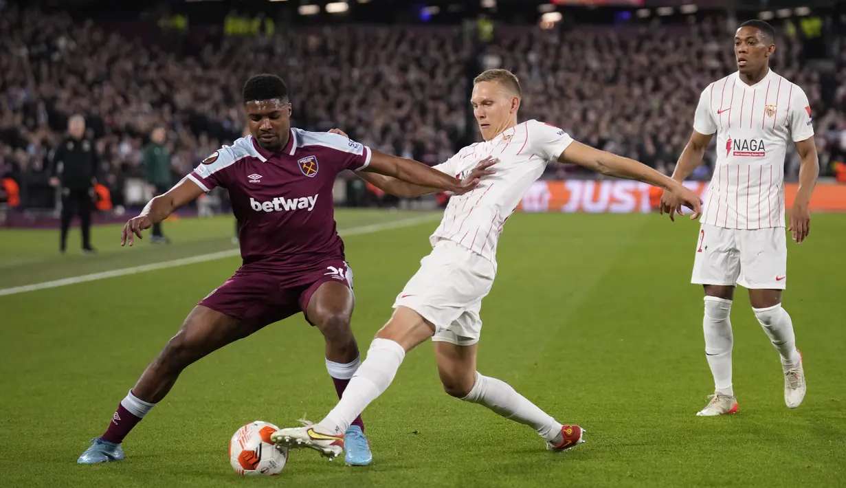 Bek West Ham Ben Johnson berebut bola dengan bek Sevilla Jules Kounde pada leg kedua Liga Europa 2021/2022 di Stadion London, Jumat (18/3/2022) dini hari WIB. West Ham United menang dramatis atas Sevilla dengan skor 2-0. (AP Photo/Matt Dunham)