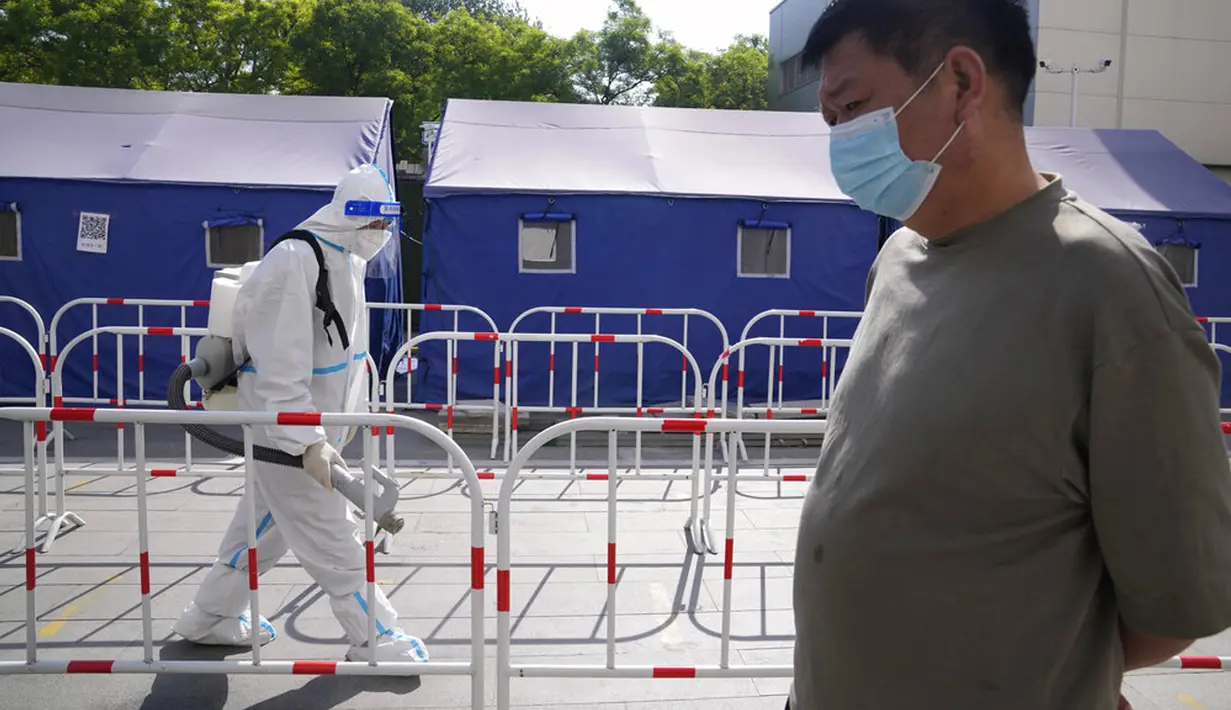 <p>Seorang warga mengantre untuk tes COVID-19 saat seorang pekerja mendisinfeksi pembatas di Beijing, China, Selasa (3/5/2022). China telah berpegang teguh pada pendekatan ketat 'Nol COVID' yang membatasi perjalanan, menguji massal seluruh kota, dan mendirikan fasilitas sementara yang luas untuk mencoba mengisolasi setiap orang yang terinfeksi. (AP Photo/Ng Han Guan)</p>