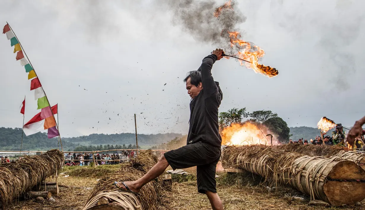 Seorang peserta menyalakan meriam yang terbuat dari batang pohon dengan menggunakan karbit dan air untuk menciptakan suara ledakan selama Festival Kuluwung, di Sukasirna, Jawa Barat, pada tanggal 5 April 2025. (ADITYA AJI/AFP)