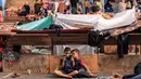 Seorang anak duduk di samping anak lainnya yang sedang bermain ponsel di taman bermain sekolah yang dikelola oleh Badan Bantuan dan Pekerjaan PBB untuk Pengungsi Palestina (UNRWA), 25 Oktober 2023. (MAHMUD HAMS/AFP)