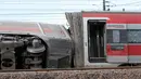 Gerbong kereta tergeletak di sisinya setelah sebuah kereta tergelincir di dekat Lodi, Italia utara, Kamis (6/2/2020). Penyelidikan sedang dilakukan terkait kecelakaan yang menewaskan dua pekerja kereta api itu. (AP/Antonio Calanni)