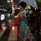 Seorang wanita Jepang tersenyum mengenakan pakaian tradisional saat berjalan di jalan setelah menghadiri peragaan busana kimono di Oita (18/10/2019). Pada zaman sekarang, kimono berbentuk seperti huruf "T", mirip mantel berlengan panjang dan berkerah. (AP Photo/Christophe Ena)