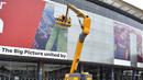 Pekerja menghapus poster yang menampilkan pemain depan Barcelona asal Argentina Lionel Messi di stadion Camp Nou di Barcelona (10/8/2021). Para pendukung PSG berharap untuk melihat pemain asal Argentina itu bergabung ke klub milik Qatar setelah hengkang dari Barcelona. (AFP/ Pau Barrena)