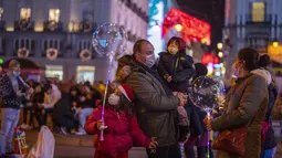 Orang-orang yang memakai masker menikmati lampu Natal di pusat kota Madrid, Rabu (22/12/2021). PM Spanyol Pedro Sanchez mengadakan rapat Kabinet khusus untuk mengesahkan undang-undang yang mewajibkan penggunaan masker di luar ruangan di tengah lonjakan rekor kasus COVID-19. (AP Photo/Manu Fernandez)