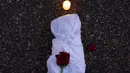 Bunga mawar kemudian diletakkan di atas kantong-kantong mayat palsu itu sementara para demonstran memegang papan-papan bertuliskan kata-kata. (AP Photo/Andrew Harnik)