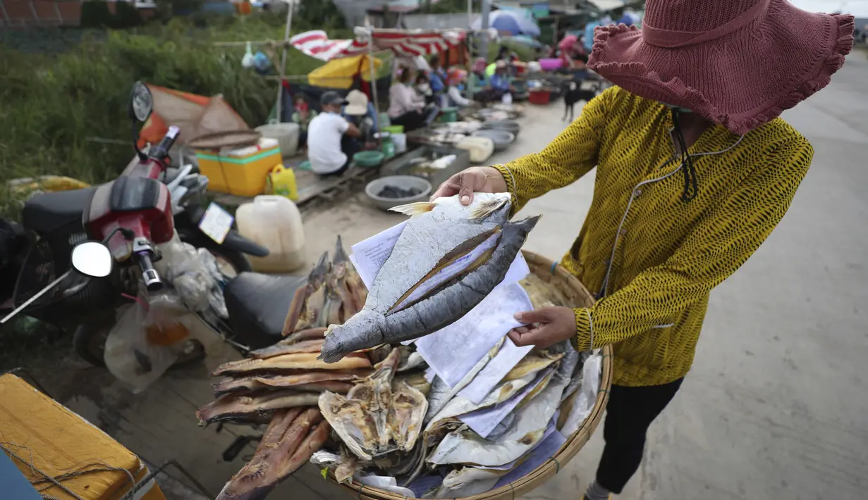 Seorang pedagang menjual ikan di sepanjang trotoar dekat desa Prek Pnov di Phnom Penh, Kamboja, Kamis (5/8/2021). Prek Pnov terkenal dengan peternakan ikannya dan memasok banyak pasar di Phnom Penh. (AP Photo/Heng Sinith)