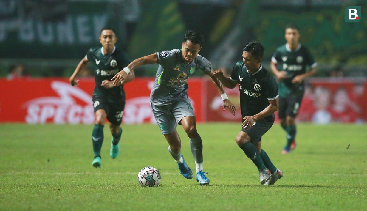 Pemain Persebaya Surabaya, Koko Ari Araya (kiri) berebut bola dengan pemain Persikabo 1973, Munadi dalam laga pekan pertama BRI Liga 1 2022/2023 antara Persikabo 1973 melawan Persebaya Surabaya di Stadion Pakansari, Bogor, Senin (25/7/2022) malam WIB. (Bola.com/M Iqbal Ichsan)