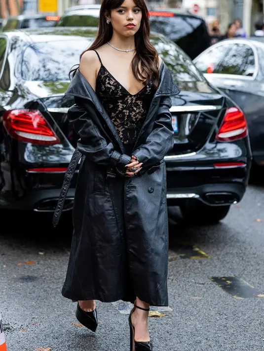 <p>Dalam perjalanannya ke Paris Fashion Week untuk show Valentino, ini penampilan Jenna Ortega. Ia mengenakan mantel parit kulit hitam yang panjang untuk menyembunyikan gaun renda tipisnya yang juga berwarna hitam.</p>