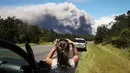 Seorang wanita berada di mobilnya mengambil gambar kepulan abu vulkanik dari gunung berapi Kilauea di Big Island Hawaii (15/5). (Mario Tama/Getty Images/AFP)