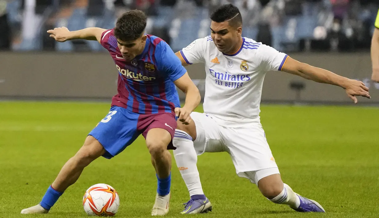 Gelandang Real Madrid, Casemiro berusaha merebut bola dari pemain Barcelona, Abdessamad pada semifinal Piala Super Spanyol di Stadion King Fahd di Riyadh, Arab Saudi, Kamis (13/1/2022). Real Madrid akan bertemu pemenang Atletico Madrid vs Athletic Bilbao di Final. (AP Photo/Hassan Ammar)