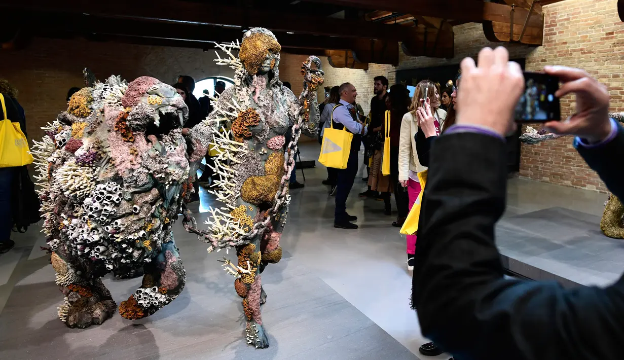 Pengunjung mengambil gambar patung yang berjudul "Lion Woman of Asit Mayor" dalam pameran seniman Inggris Damien Hirst di Venice, Italia (6/4). (AFP Photo/Miguel Medina)