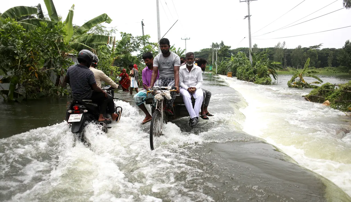 Warga melintasi jalan yang terendam banjir di Munshiganj, pinggiran Dhaka, Bangladesh, Senin (27/7/2020). Hingga 27 Juli 2020, hampir separuh dari wilayah Bangladesh masih terendam banjir. (Xinhua)