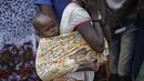 Pengungsi Sudan Selatan menggendong anaknya di sebuah pusat transit pengungsi di Kuluba, Uganda utara, Kamis (8/6). Mereka melarikan diri dari perang saudara di Sudan Selatan yang telah memakan korban puluhan ribu jiwa. (AP Photo / Ben Curtis)