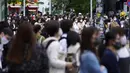 Orang-orang mengenakan masker untuk mencegah virus corona berjalan melintasi penyeberangan pejalan kaki pada awal liburan "Minggu Emas" Jepang di distrik Shibuya, Tokyo, Kamis (29/4/2021). (AP Photo/Eugene Hoshiko)