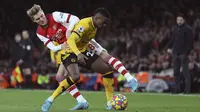 Bek Wolverhampton Wanderers Nelson Semedo berebut bola dengan gelandang Arsenal Martin Odegaard pada partai tunda pekan ke-20 Liga Inggris di Emirates Stadium, Jumat (25/2/2022) dini hari WIB. Arsenal menang dramatis 2-1 berkat dua gol di menit akhir. (AP Photo/Ian Walton)