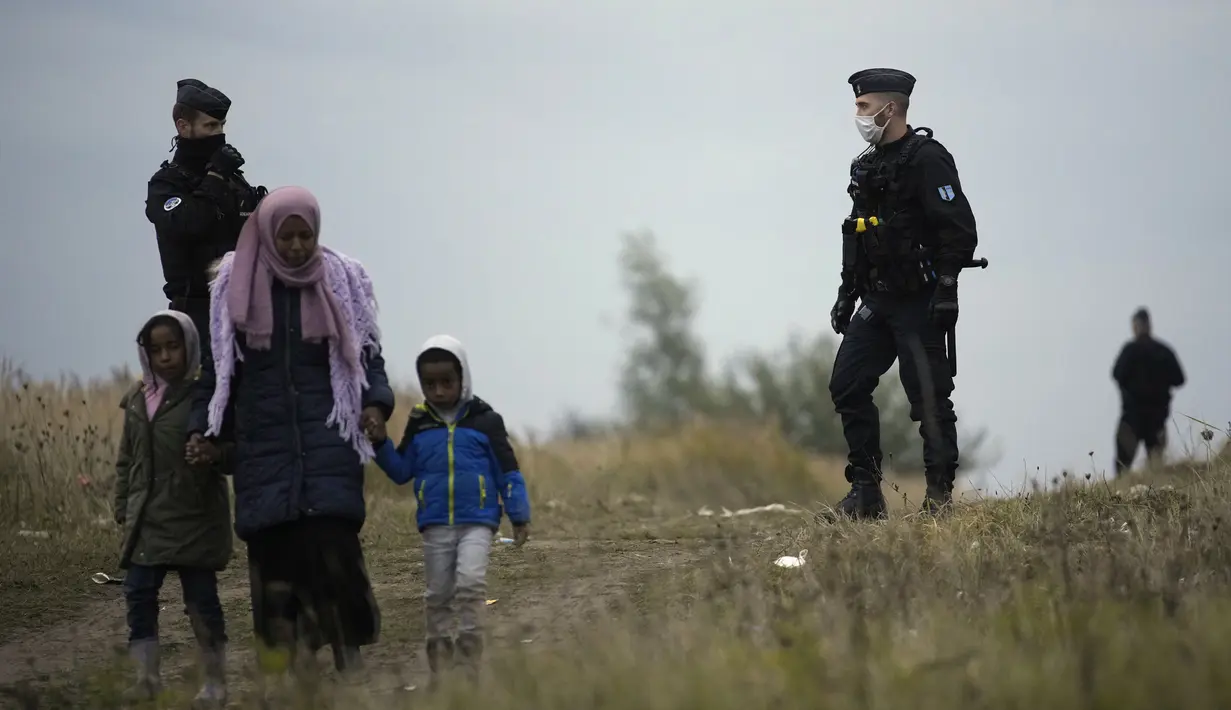 Petugas polisi berpatroli di dekat kamp migran di Calais, Prancis pada 14 Oktober 2021. Dalam praktik berbahaya dan berpotensi mematikan, beberapa imigran mencoba melewati terowongan menuju Inggris yang dijaga ketat yang menghubungkan kedua negara dengan bersembunyi di truk. (AP/Christophe Ena)
