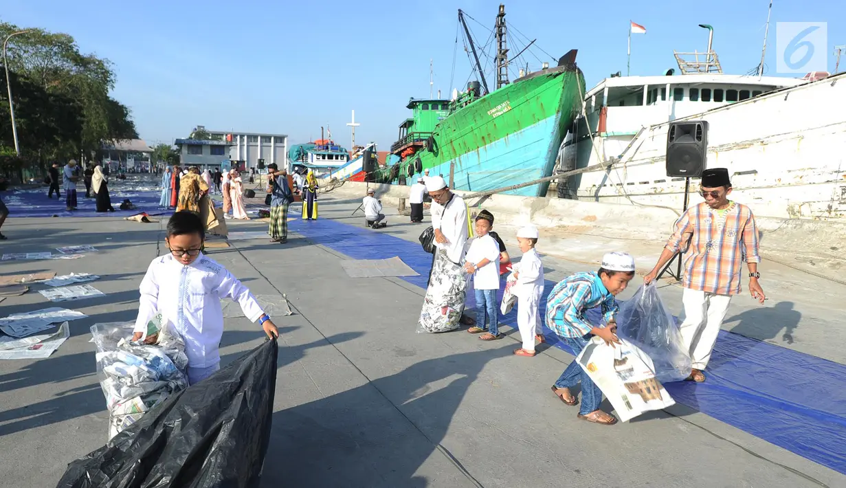 Anak-anak memunguti koran bekas usai pelaksanaan salat Idul Fitri di kawasan Pelabuhan Sunda Kelapa, Jakarta, Rabu (5/6/2019). Umat muslim seluruh Indonesia merayakan Hari Raya Idul Fitri 1440 Hijriah setelah sebelumnya melaksanakan puasa Ramadan selama sebulan penuh. (merdeka.com/Arie Basuki)