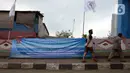 Warga melintasi spanduk penolakan PP Nomor 85 Tahun 2021 KKP terkait tarif atas jenis PNBP di Pelabuhan Muara Angke, Jakarta, Sabtu (9/10/2021). Dengan terbitnya PP Nomor 85 Tahun 2021, PNBP untuk para nelayan mengalami kenaikan sebesar 600 persen dari tarif biasanya. (merdeka.com/Imam Buhori)